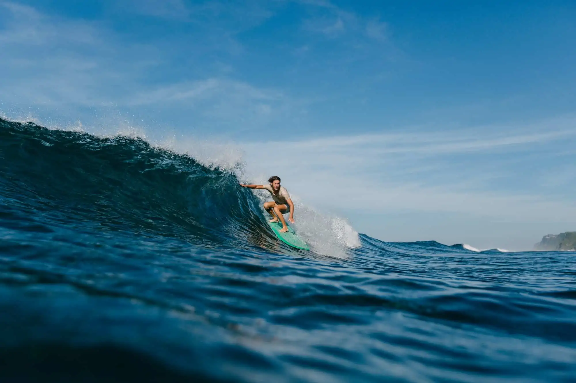 professional surfer in wet t-shirt riding waves on surfboard on sunny day