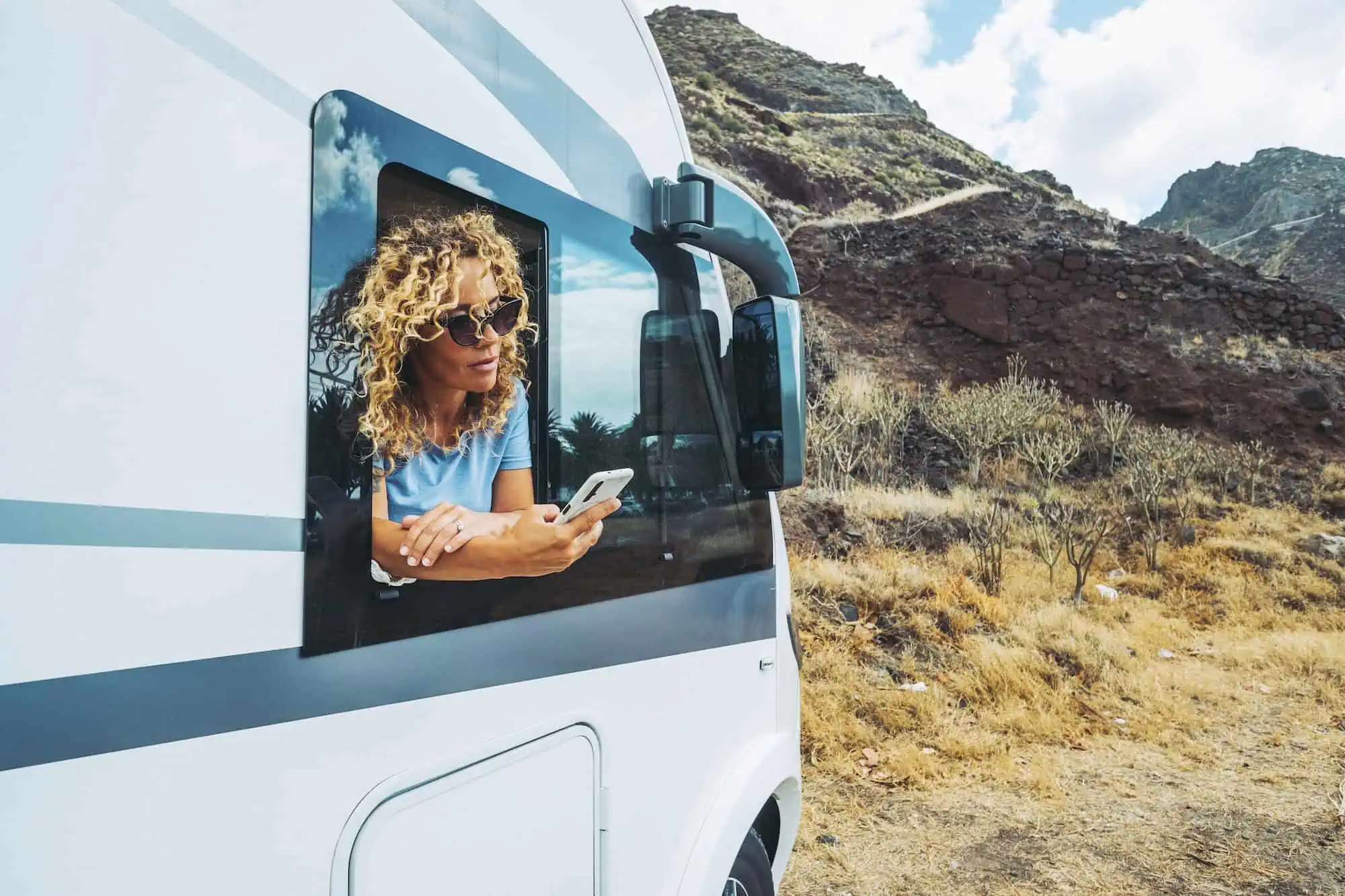 One independent woman using phone outside the window of her alternative home camper van