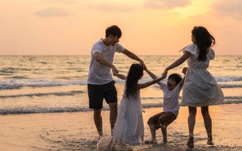 Asian young happy family enjoy vacation on beach in the evening.