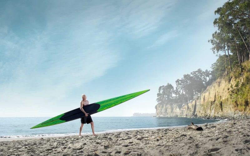 Surfer carrying surfboard onto beach, Santa Cruz, California, USA