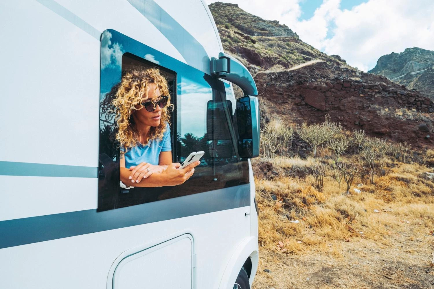 One independent woman using phone outside the window of her alternative home camper van