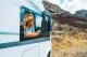 One independent woman using phone outside the window of her alternative home camper van