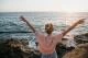 Rear view of young woman at the sea with raised arms, Sunset Cliffs, San Diego, California, USA